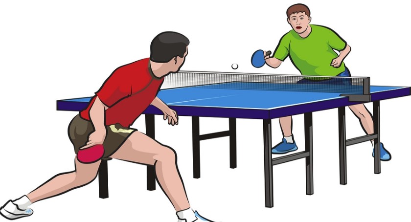 Na zdjęciu znajdują się zawodnicy przy stole grający w tenisa stołowego